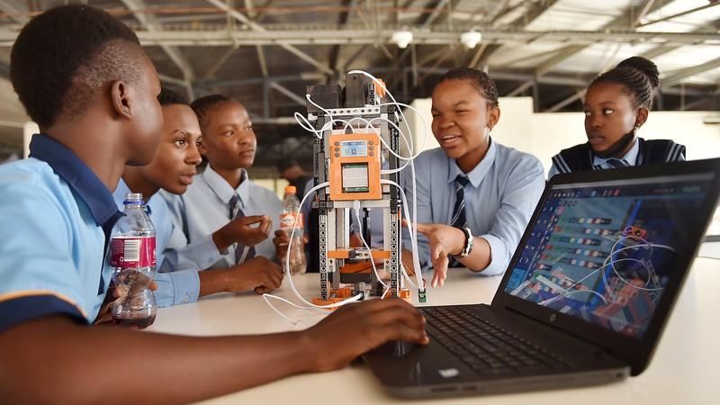 High school learners programming a robot on a laptop